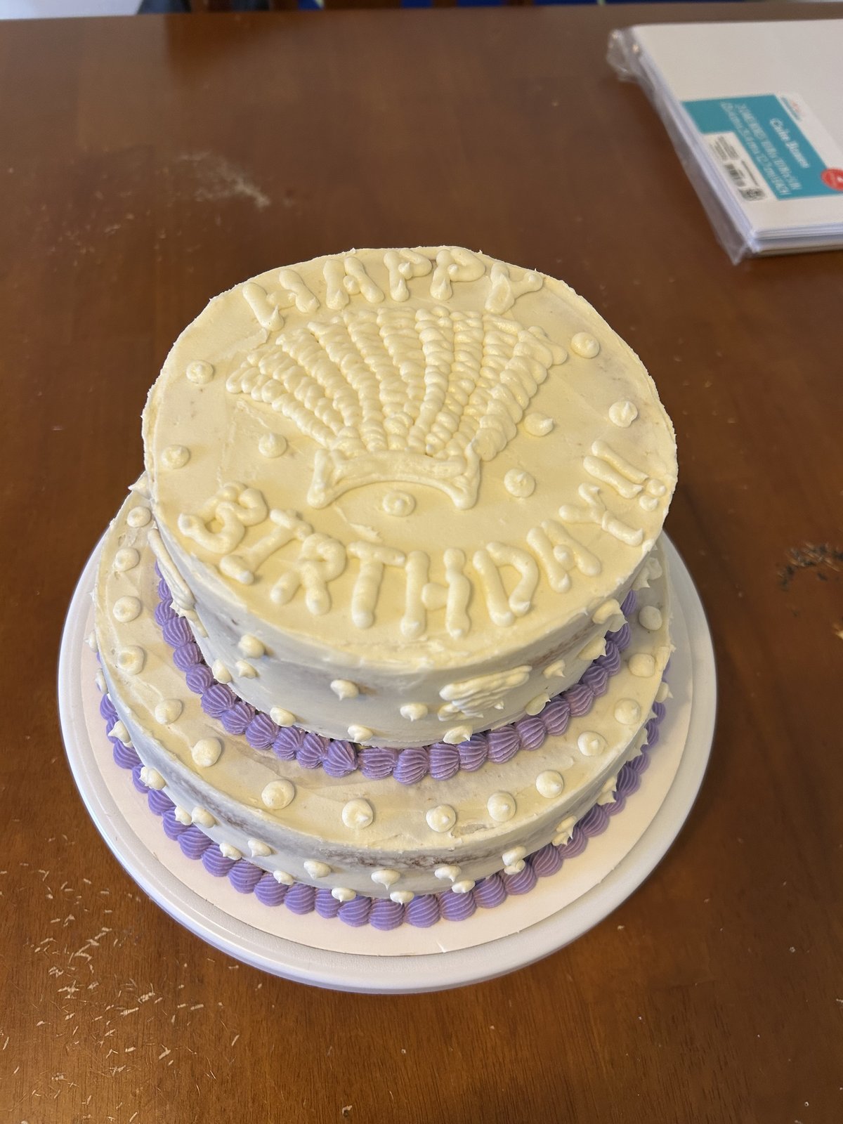 Two tier birthday cake with purple piping